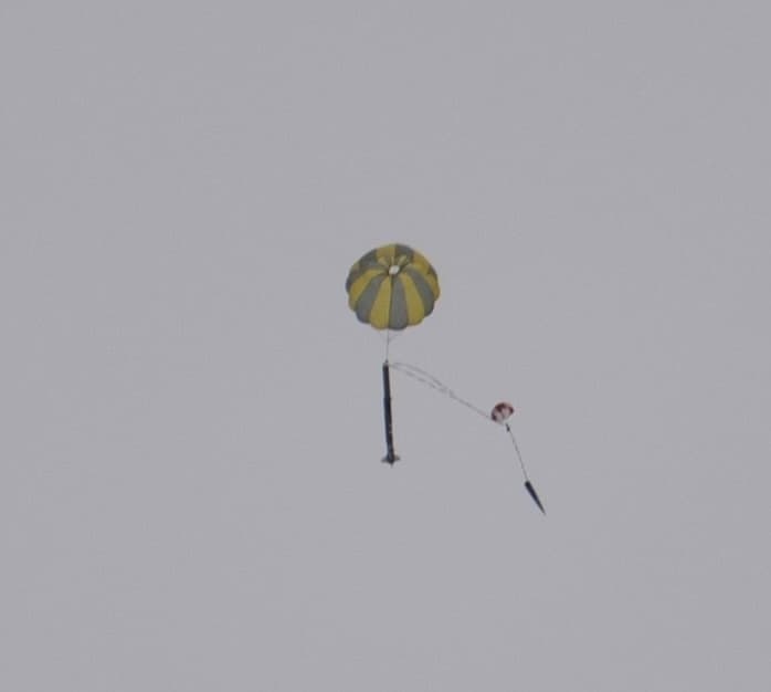 Rocket descending under a deployed parachute